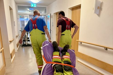 Feuerwehrangehörige üben die Rettung einer nicht gehfähigen Person mit einer Evakuierungsdecke und einer Matratze.
