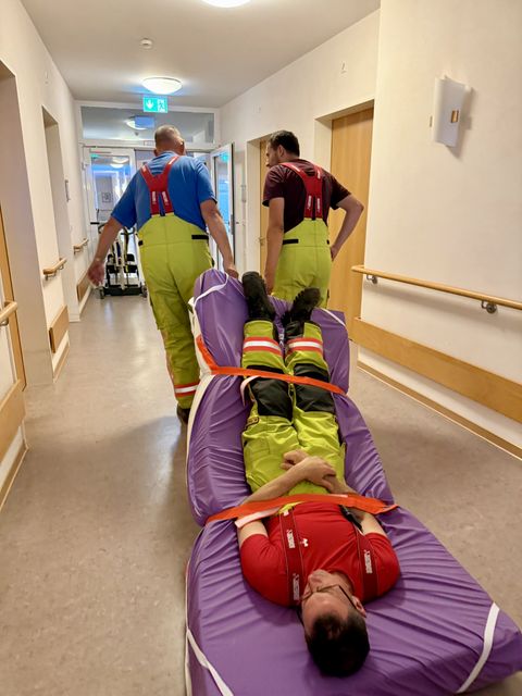 Feuerwehrangehörige üben die Rettung einer nicht gehfähigen Person mit einer Evakuierungsdecke und einer Matratze.