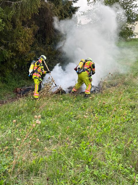 Zwei Feuerwehrleute unter Atemschutz ziehen das Brandgut auseinander.